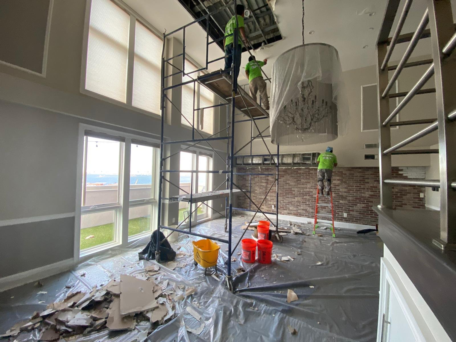 Anajur Construction crew on multi-elevation restoration scaffolding at a Staten Island residential project, with floor-to-ceiling windows visible